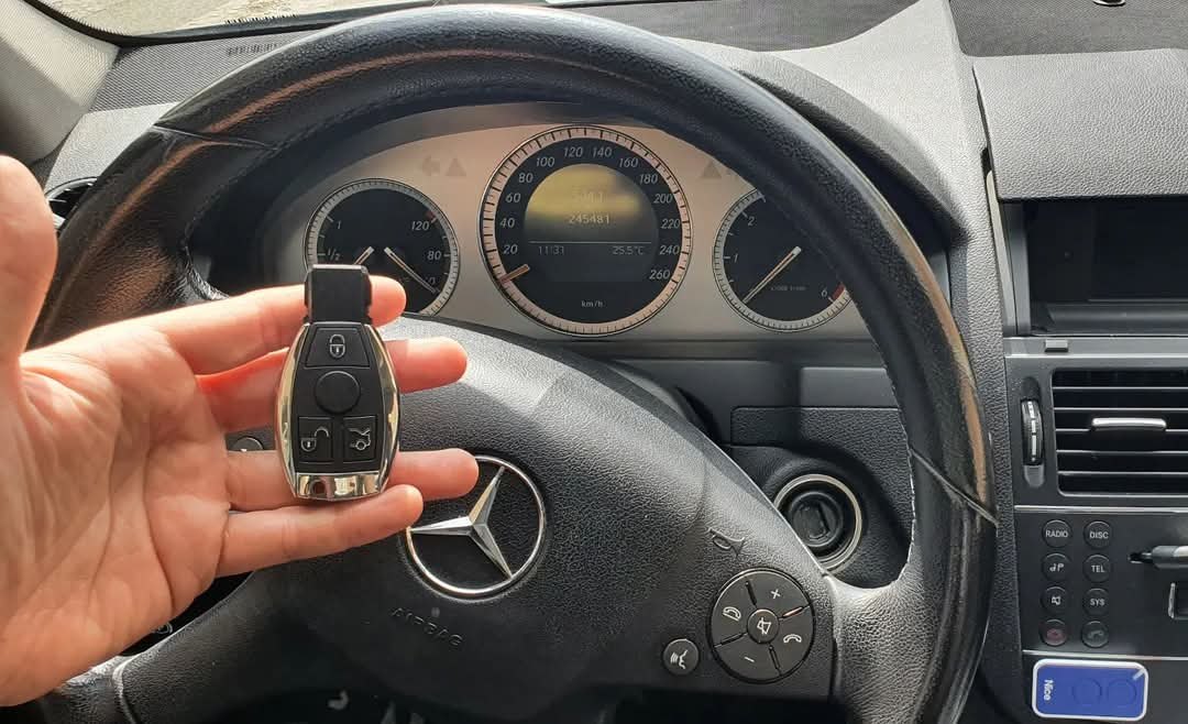 Mano con una llave de mando de Mercedes delante del volante del coche