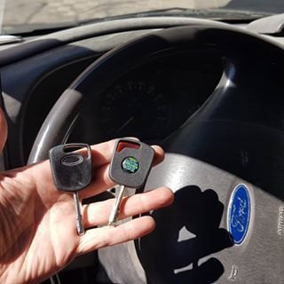Dos llaves de coche Ford en la mano, delante del volante