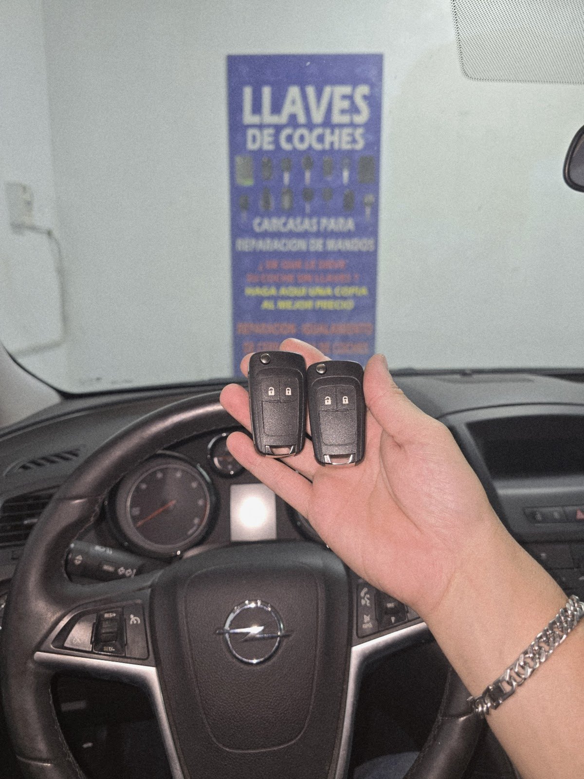 Dos llaves de mando plegables de Opel delante del cartel de llaves de coches